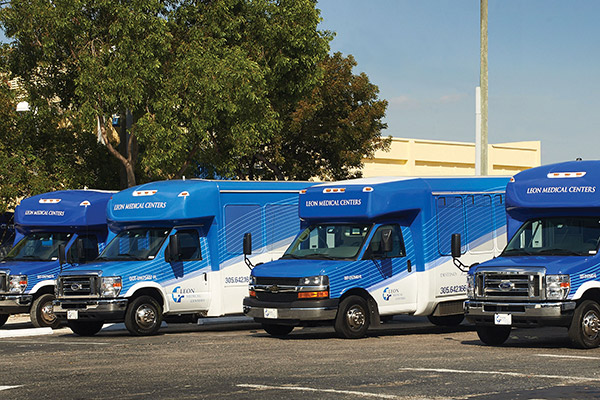 Four Leon Medical Centers buses are parked in a parking lot