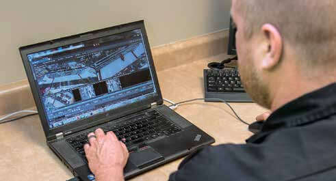 Image of a man reviewing security footage from a grocery store on his laptop.